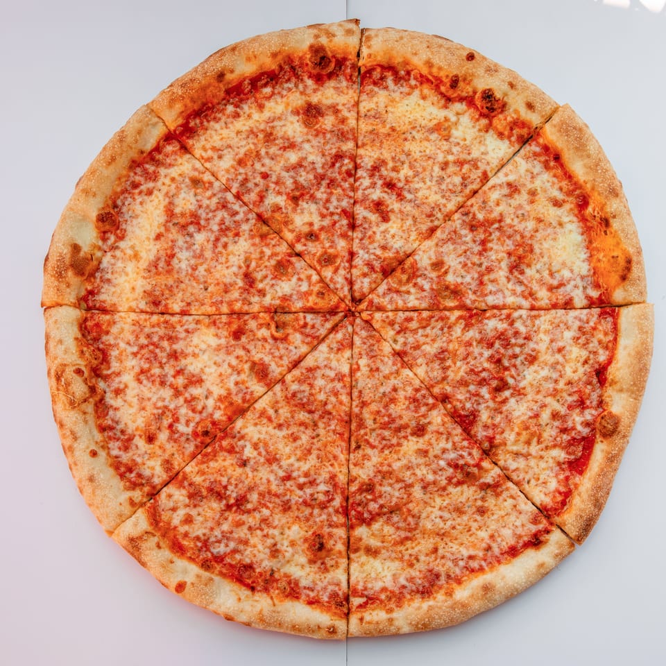 Whole cheese pizza with tomato sauce and golden crust, cut into slices on a light background.